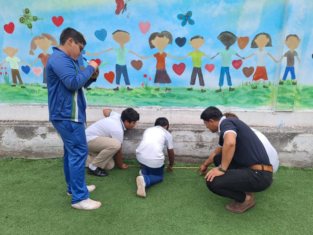 Students in Galapagos use tape measures to determine the perimeter and area of their school courtyard.